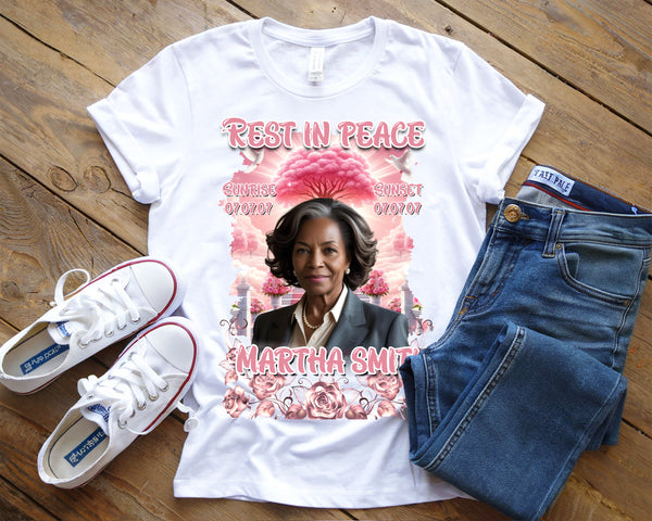 White t-shirt with a graphic design of a woman's portrait and text, paired with white sneakers and blue jeans on a wooden surface.